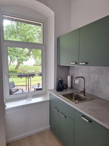 een keuken met een wastafel en een raam met een tafel bij FeWo Sonnenberg in Chemnitz