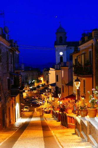 a city street at night with a clock tower at Montecelio Golden House in Guidonia