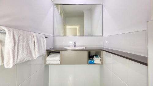 a white bathroom with a sink and a mirror at Best Western Cattle City Motor Inn in Rockhampton
