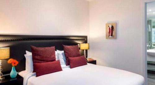 a bedroom with a large white bed with red pillows at Oaks Queenstown Club Suites in Queenstown