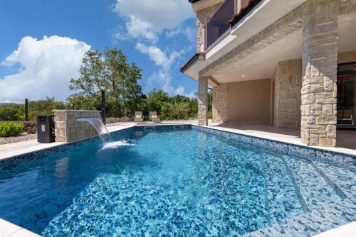 a swimming pool with a waterfall in a house at Villa Divina in Milohnići