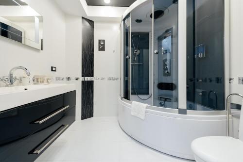 a white bathroom with a shower and a sink at ERA RENT Apartments 2 in Chişinău