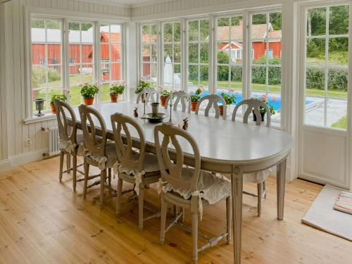 a dining room with a table and chairs and windows at Countryside Farm With Pool In Västergötland in Ljung