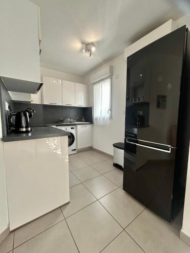 Il comprend une cuisine équipée d'un réfrigérateur noir et de placards blancs. dans l'établissement Villa lumière, à Cannes