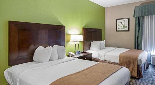 two beds in a hotel room with green walls at Quality Suites in Sulphur