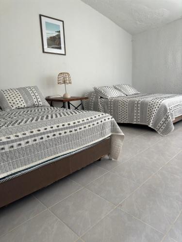 two beds in a room with a tiled floor at Rosarito By The Sea in Rosarito