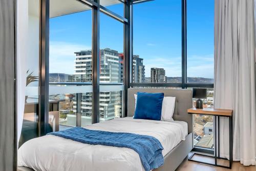a bedroom with a bed and a large window at Cityscape Haven - CBD retreat with an array of Hotel Amenities in Adelaide