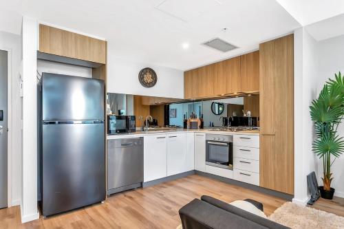 a kitchen with a stainless steel refrigerator and white cabinets at Cityscape Haven - CBD retreat with an array of Hotel Amenities in Adelaide