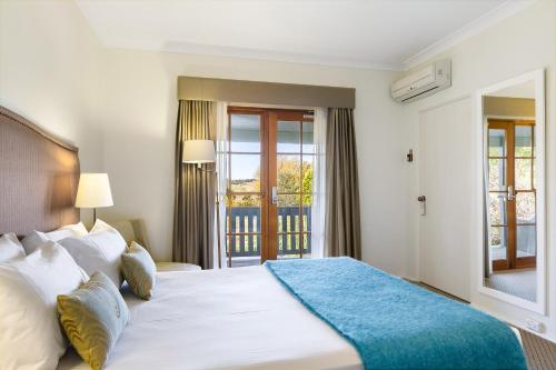 a bedroom with a large bed and a balcony at Peppers Manor House in Sutton Forest