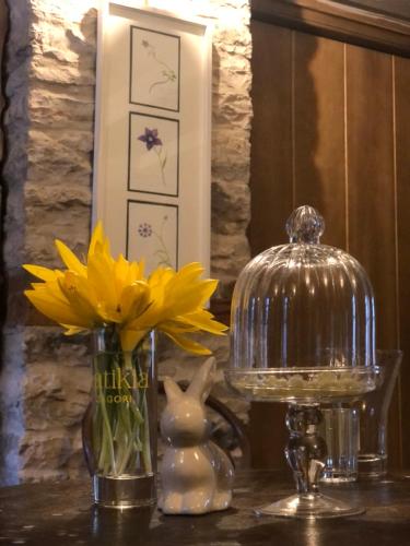 a table with a vase of yellow flowers and a lamp at KATIKIA ZAGORI in Vitsa