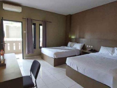 a hotel room with two beds and a table at Grand Mutiara Hotel in Pangandaran