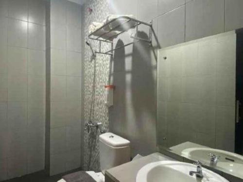 a bathroom with a sink and a toilet and a mirror at Grand Mutiara Hotel in Pangandaran