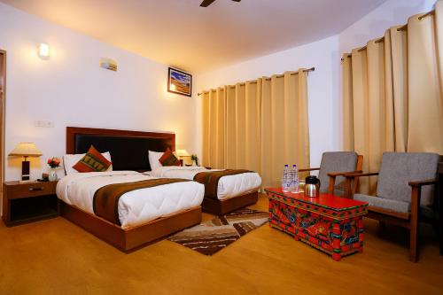 a bedroom with two beds and a chair and a table at Hotel Grand Nubra in Deskit