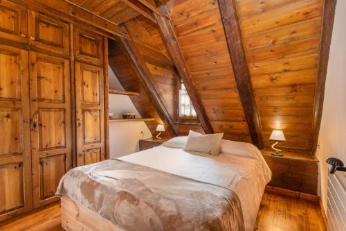 a bedroom with a bed in a room with wooden walls at Casa aranesa en centro de Arties in Arties