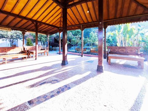 a pavilion with benches in a park with the sun shining at Pondok Daun D Martin Mitra RedDoorz near UMY in Ngingas