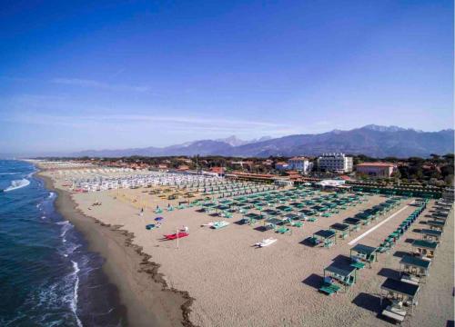 a beach with chairs and umbrellas and the ocean at Suite a 100mt dal Duomo - Living Gallery in Pietrasanta