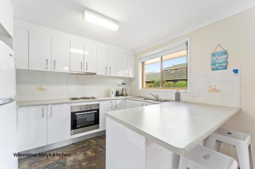 a kitchen with white cabinets and a white counter top at Woonona Stays in Woonona