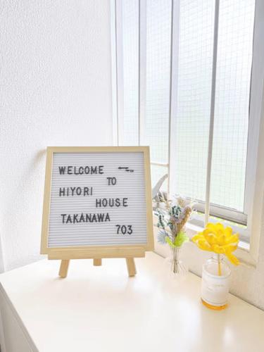 a sign on a window sill with flowers and a window at 高輪ー703 in Tokyo