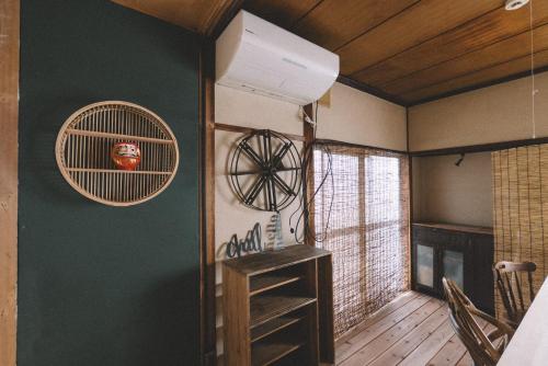a room with a green wall with a fan at guesthouse TANDEM in Matsumoto