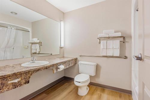 a bathroom with a toilet and a sink and a mirror at Days Inn & Suites by Wyndham West Edmonton in Edmonton