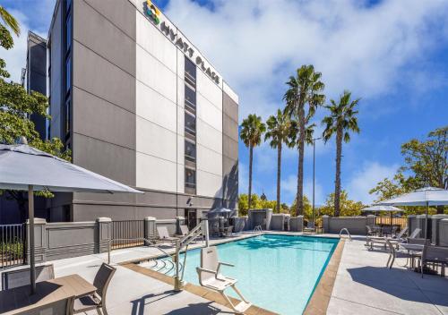 a pool at a hotel with chairs and umbrellas at Hyatt Place Sacramento Rancho Cordova in Rancho Cordova