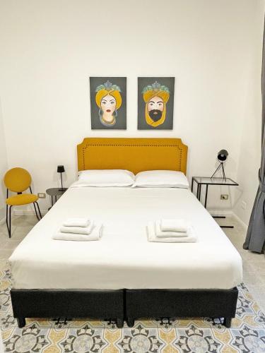 a bed in a room with two paintings on the wall at ISOLA - Smart ApartHotel in Messina