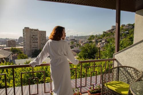 a woman in a white dress standing on a balcony at Hillside Guest House in Yerevan