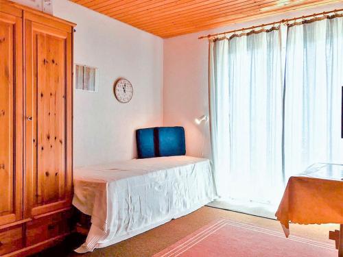 a bedroom with a blue chair and a window at Studio "Renner" in Les Crosets