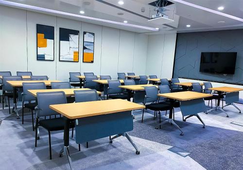 an empty classroom with tables and chairs and a tv at Hilton Bahrain in Manama