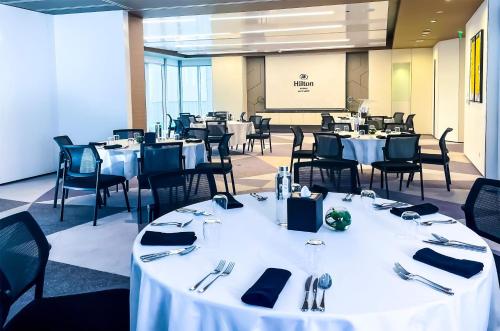 a dining room with white tables and chairs at Hilton Bahrain in Manama