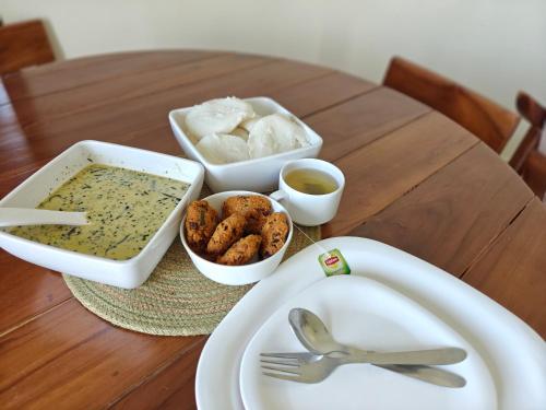 a table with a plate of food and a bowl of soup at Nilgiri Woodlands Luxury Service Apartments in Mysore