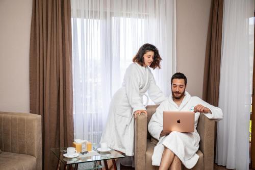 a woman standing next to a man sitting in a chair with a laptop at Hillside Guest House in Yerevan