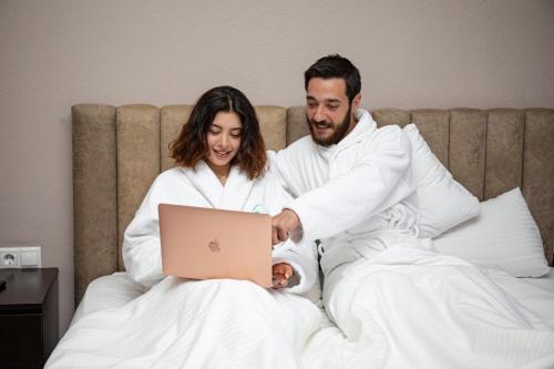 a man and a woman in bed with a laptop at Hillside Guest House in Yerevan