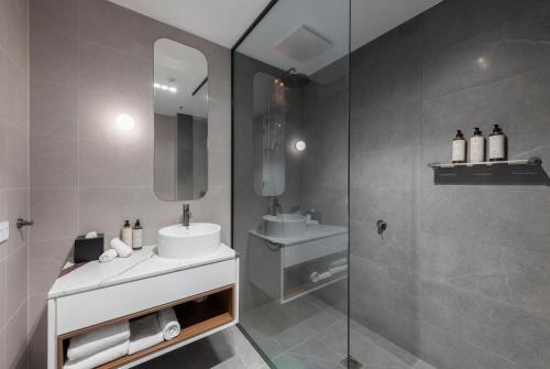 a bathroom with a sink and a glass shower at TRYP Adelaide by Wyndham in Adelaide