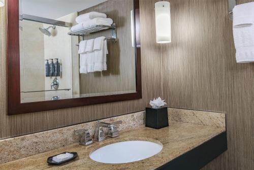 a bathroom with a sink and a mirror and towels at Courtland Grand Hotel, Trademark Collection by Wyndham former Sheraton Atlanta in Atlanta