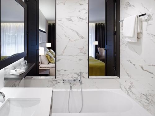 ein Badezimmer mit einer Badewanne, einem Waschbecken und einem Spiegel in der Unterkunft Hotel Kasteel Bloemendal in Vaals