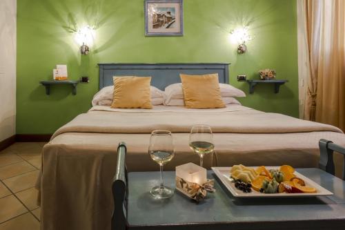 a bedroom with a bed with a tray of food and wine glasses at Il Melograno Agriturismo & SPA in Pianello