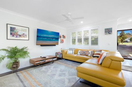 a living room with a yellow couch and a table at Treetops on Seabreeze in Toormina