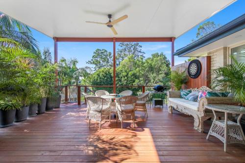 a deck with a table and chairs and a couch at Treetops on Seabreeze in Toormina