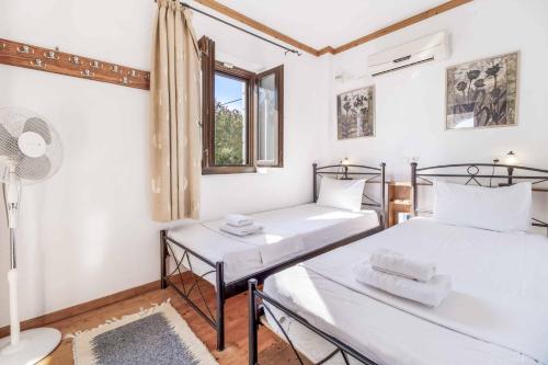 two beds in a room with a window at Villa Mulberry in Stoupa