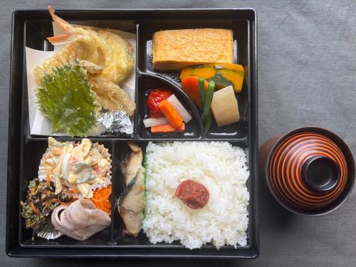 una bandeja negra con arroz y diferentes tipos de comida en サポートイン南知多, en Utsumi