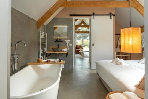 a bathroom with a tub next to a bedroom at Wellness Lodges x De IJsvogel in Voorthuizen