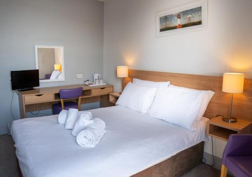 a hotel room with a bed with towels on it at The Seafront Hotel by Compass Hospitality in Llandudno