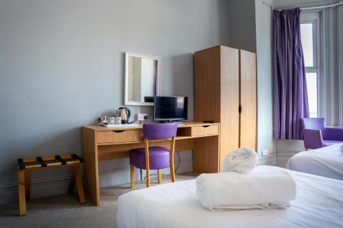 a hotel room with a desk with a computer and purple chairs at The Seafront Hotel by Compass Hospitality in Llandudno