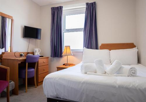 a bedroom with a bed with a desk and a window at The Seafront Hotel by Compass Hospitality in Llandudno