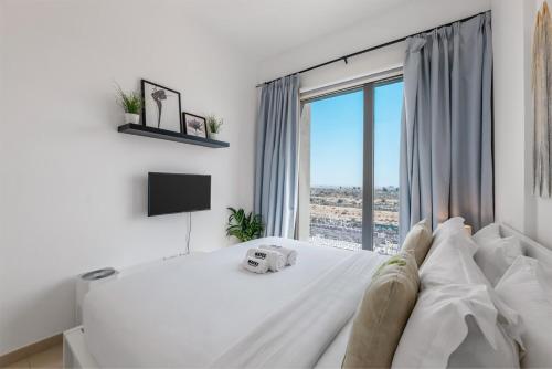 a bedroom with a white bed with a large window at Waves - Stylish Blue Haven near Town Square Park in Dubai