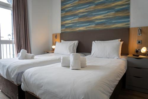 two beds in a room with a painting on the wall at The Seafront Hotel by Compass Hospitality in Llandudno