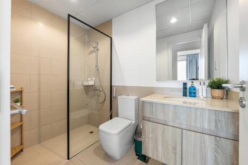 a bathroom with a toilet and a shower and a sink at Waves - Stylish Blue Haven near Town Square Park in Dubai