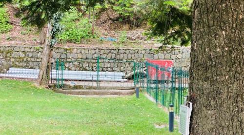 a green fence next to a stone wall and a tree at Bilour House Main Dunga Gali Bazar, nathiagali in Dunga Gali