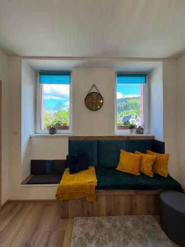 a living room with a green couch and two windows at Przystanek Piechowice in Piechowice